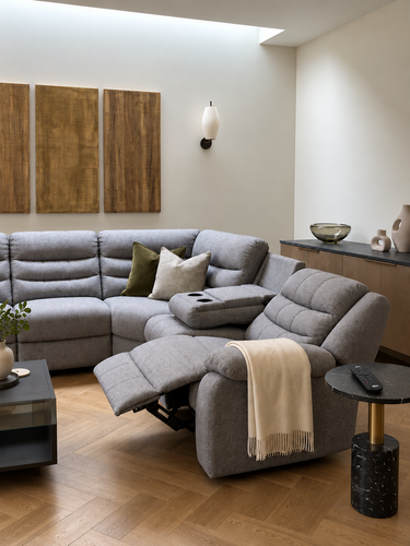 A beige jumbo-cord sofa with a scatter cushion against warm wood panelling