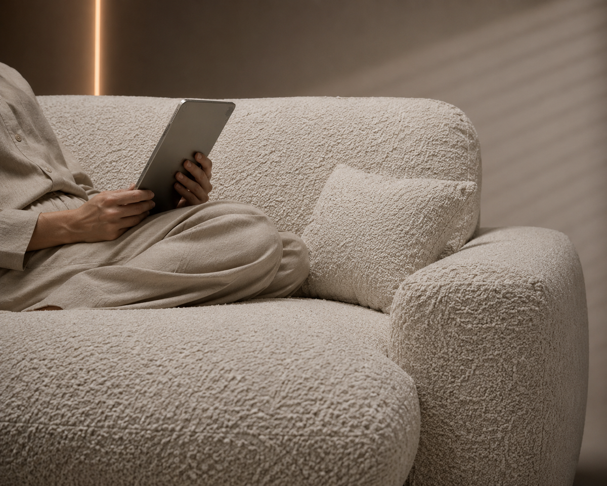A person relaxing with a tablet on a cream bouclé SofaPack sofa